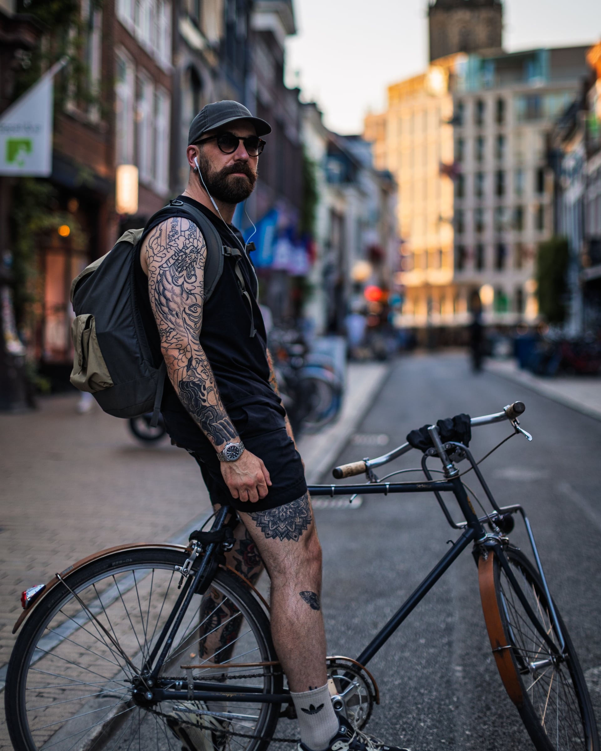 Straatportret van een man met tatoeages naast zijn fiets