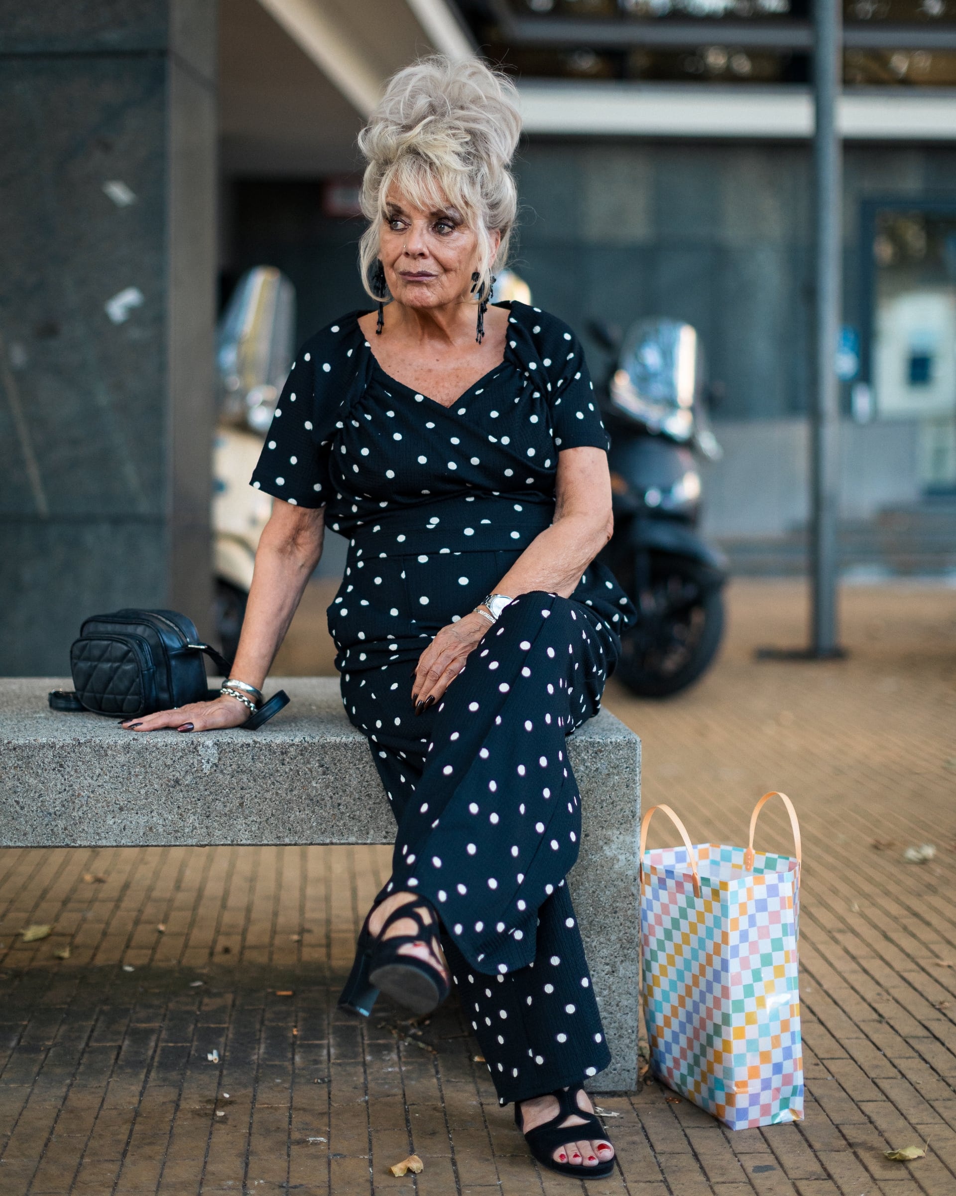 Portret van een vrouw in een gestippelde jurk op een stenen rand